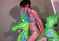 Lola rides the green dragon with a pool toy