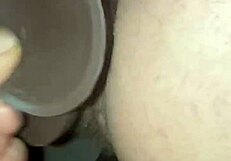 Wife ties up her man and takes turns using a massive dark colored dildo to fuck his creamy load