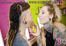 Alternative beauty with pierced nipples gives a blowjob and fuck with a strap-on to a shy teenage girl.